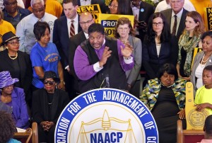 North Carolina NAACP president, Rev. William Barber, center at podium gestures as he is surrounded by supporters during a news conference at the Third Street Bethel AME Church in Richmond, Va., Tuesday, June 21, 2016.  The press conference was held to talk about the appeal before the 4th Circuit court of Appeals on North Carolina's 2013 major rewrite of voting laws. (AP Photo/Steve Helber)