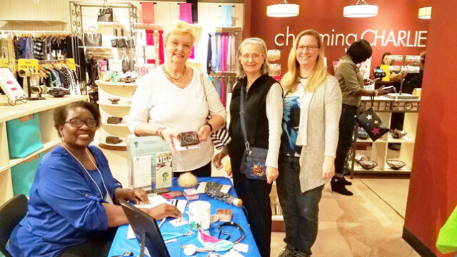 Photo 2: 
Shopping guests stop by the Empowerment Resources table manned by volunteer Elaine White, to purchase wish list items on behalf of girls in the Journey Into Womanhood program