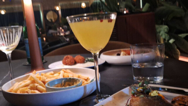 Shown are the Truffle Fries, Cocktail Sirocco and Branzino Sea Bass